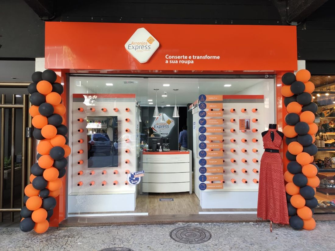 Loja Arranjos Express em rua, com serviços listados na vitrine